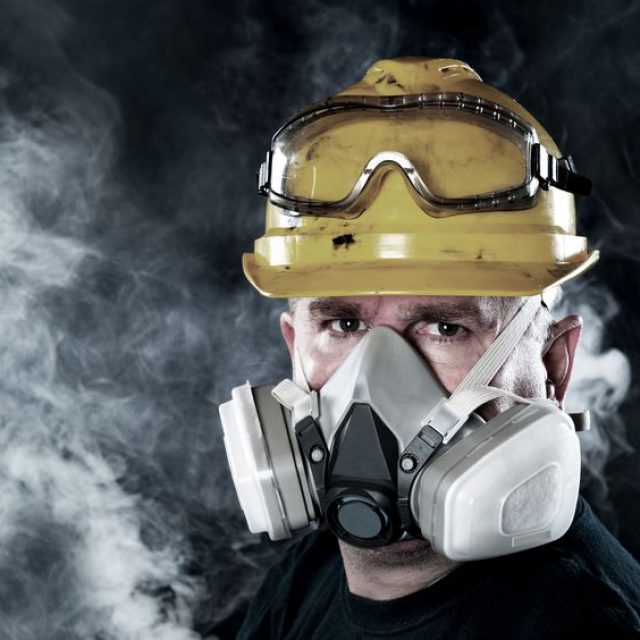 13998401 - a rescue worker wears a respirator in a smokey, toxic atmosphere.  image show the importance of protection readiness and safety.